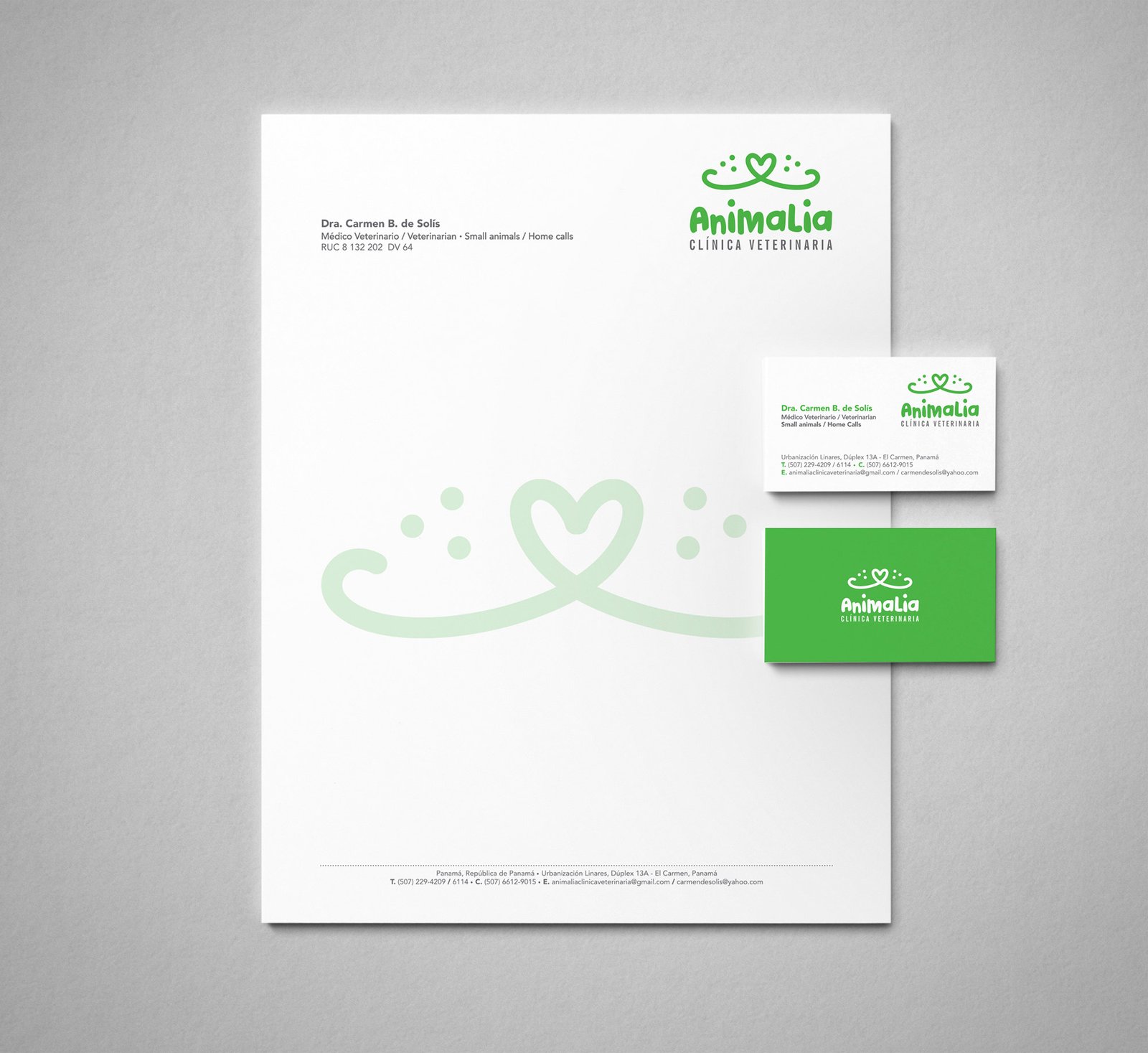 Logo Animalia - Clínica Veterinaria, montado sobre papel membrete y tarjeta de presentación. La tarjeta de presentación muestra la parte frontal y posterior. El logo es color verde, con icono de hocico de un perro o gato en forma de corazón. Fondo gris claro con textura.