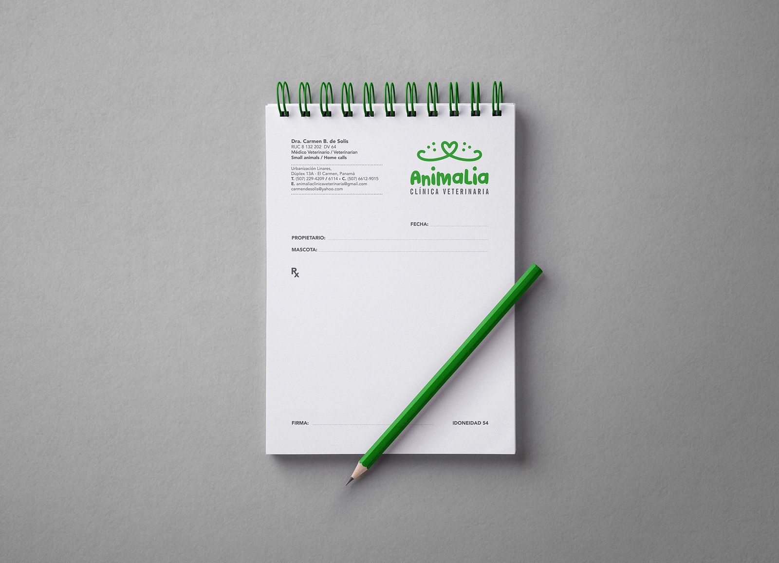 Logo Animalia - Clínica Veterinaria, montado sobre una libreta de recetas veterinarias. Sobre la libreta hay un lápiz verde. El logo es color verde, con icono de hocico de un perro o gato en forma de corazón. Fondo blanco con textura.