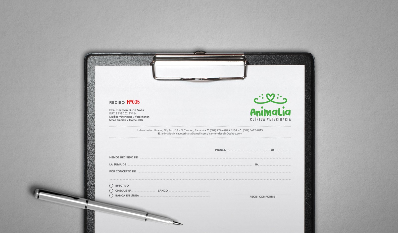 Logo Animalia - Clínica Veterinaria, montado sobre una carpeta con una hoja de formato de recibo. Sobre la hoja hay un bolígrafo blanco. El logo es color verde, con icono de hocico de un perro o gato en forma de corazón. Fondo gris claro con textura.