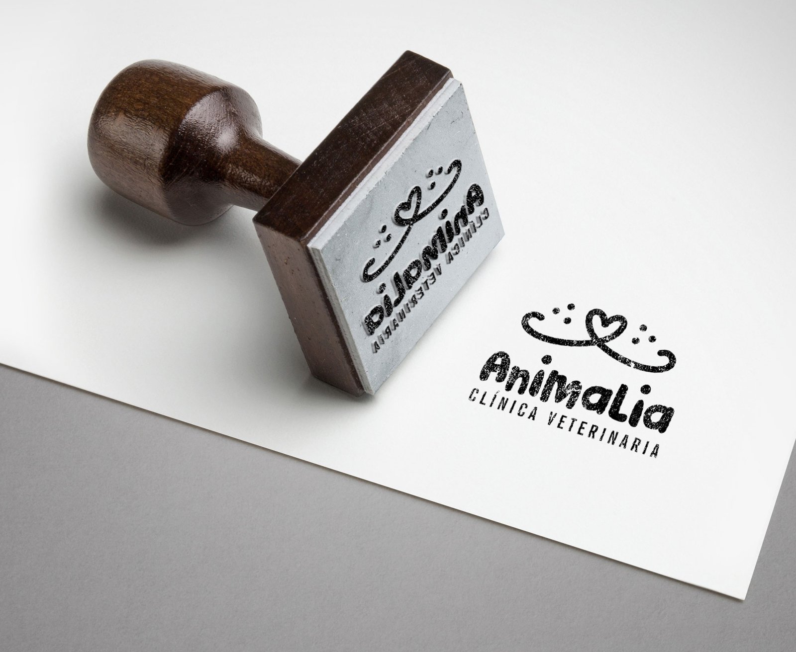 Logo Animalia - Clínica Veterinaria, montado sobre un formato de sello. El sello está estampado en tinta negra sobre una hoja en blanco. Fondo color gris.